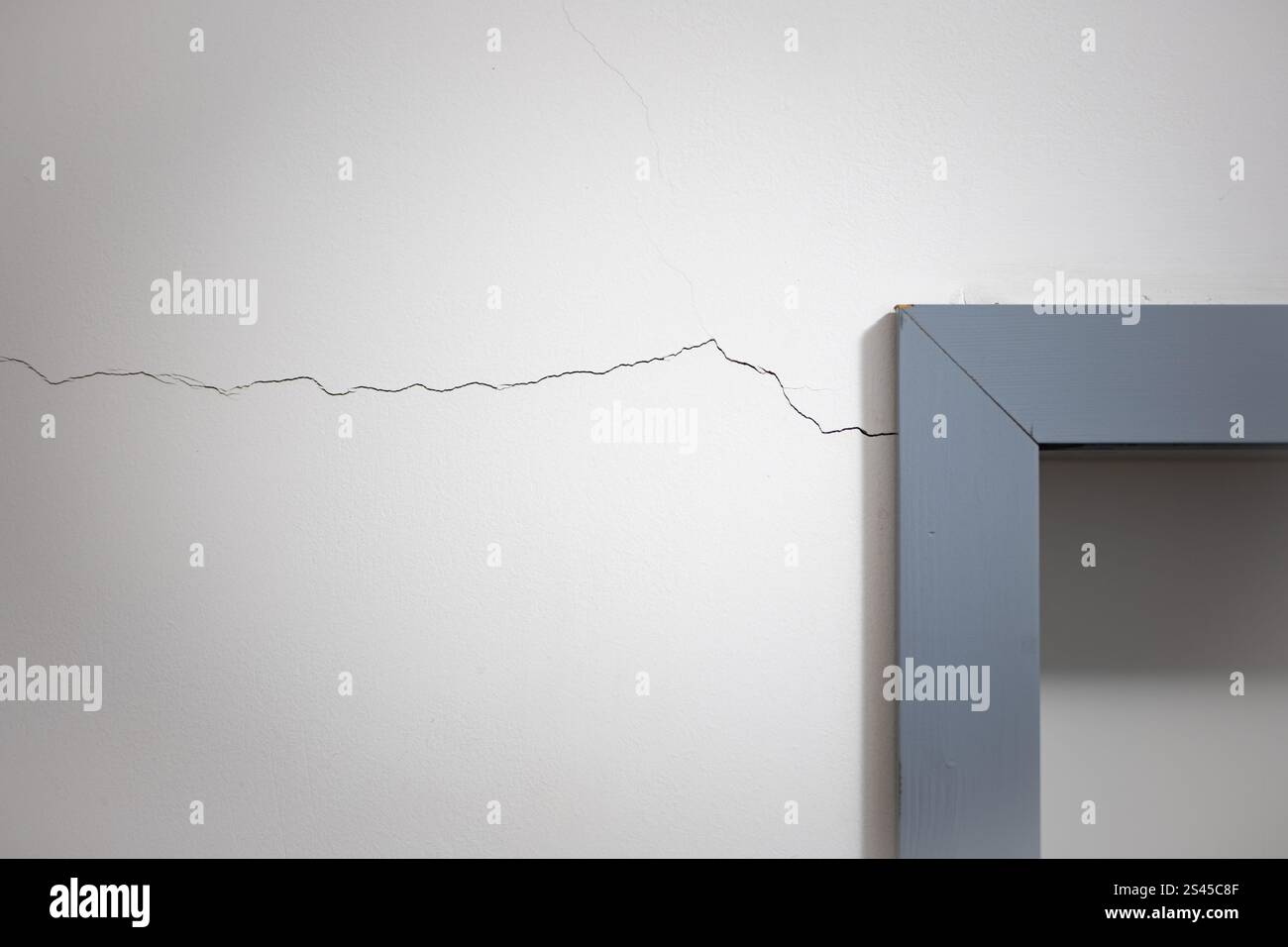Risse im Haus, weiße Wand neben dem Türrahmen, keine Leute. Stockfoto