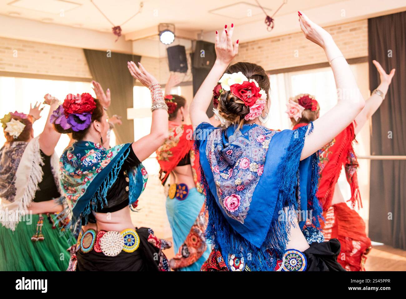 Frauen in langen Kleidern tanzen in farbigem Schal, Tänzerin im Studio, die Show im Neonnebel zeigt Stockfoto