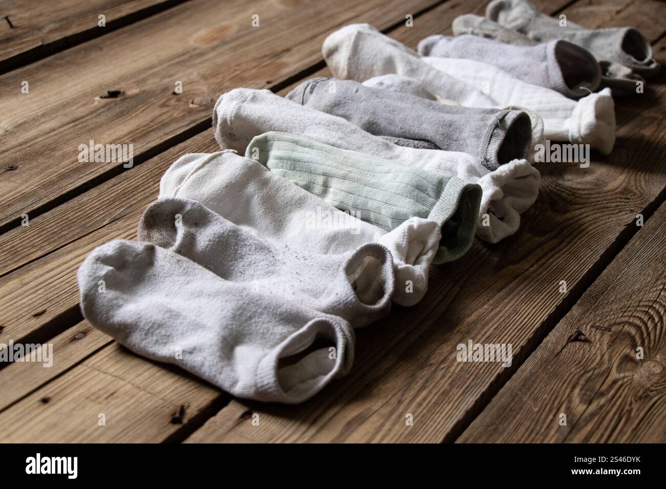 Viele Damensocken sind gefaltet und liegen auf einem Holzboden, getragene Damensocken Stockfoto