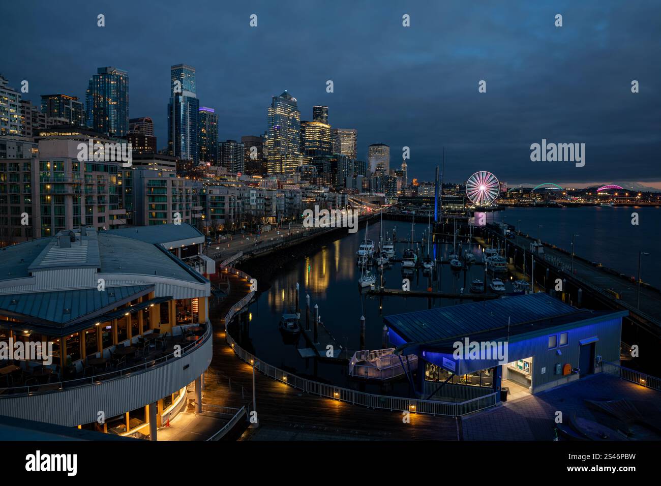 WA28095-00...WASHINGTON - Blick auf Elliot Bay, Bell Harbor Marina, Great Wheel und Seattle Uferpromenade bei Sonnenuntergang. Stockfoto