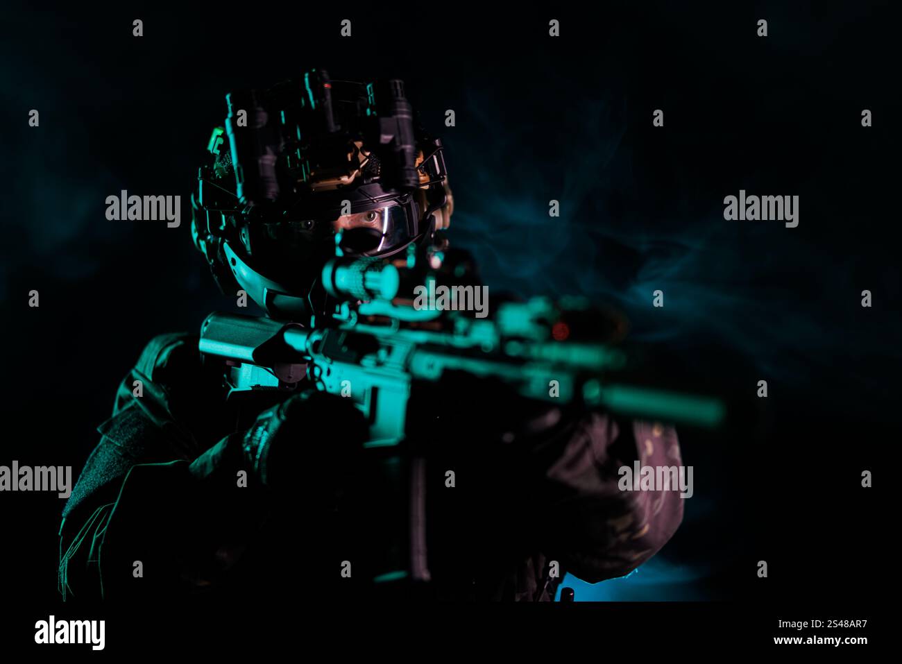 Ein Soldat in taktischer Ausrüstung, einschließlich Helm und Nachtsichtausrüstung, zielt in einer rauchigen dunklen Umgebung. Das Bild strahlt Bereitschaft aus, Tarnung, Professi Stockfoto