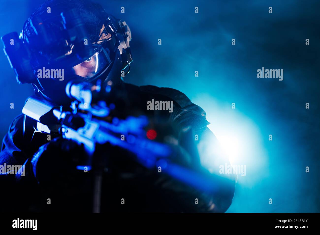 Ein professioneller taktischer Bediener ist bereit für die Aktion, der fortschrittliche Ausrüstung in einer dramatischen beleuchteten Umgebung präsentiert und die Einsatzbereitschaft unterstreicht. Stockfoto