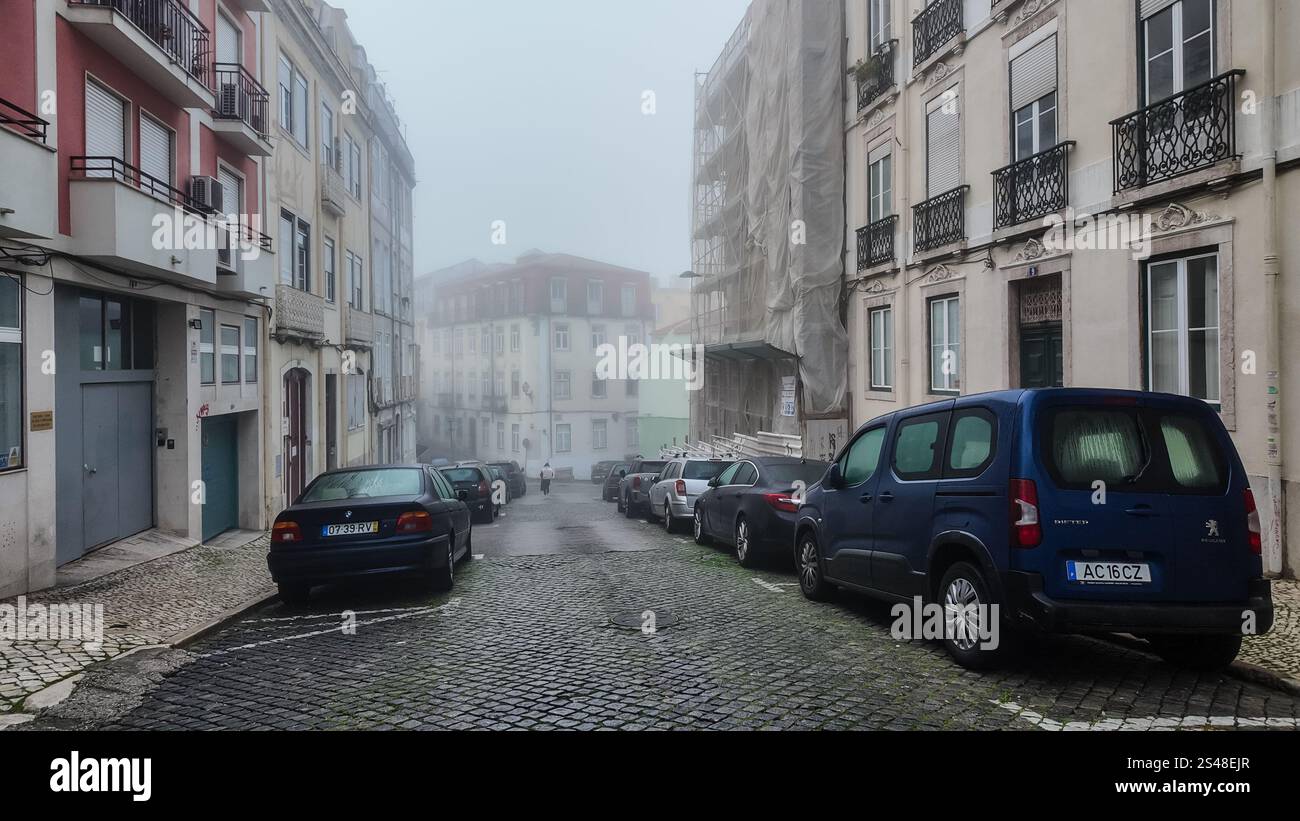 Autos, die auf beiden Seiten einer schmalen Straße in einem Wohnviertel in Intendente, Lissabon, Portugal parken. Stockfoto