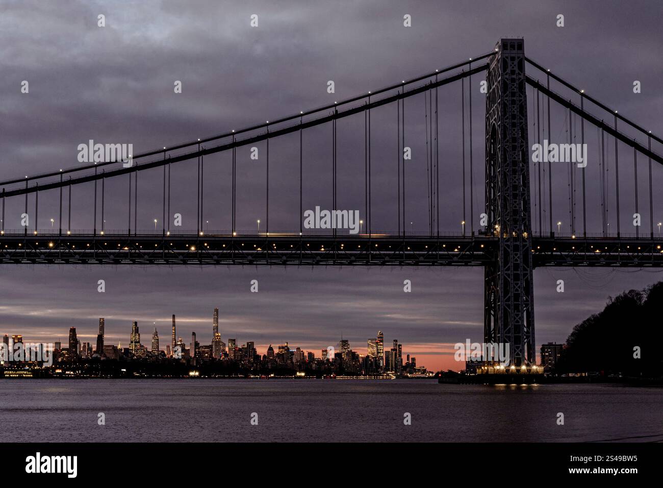 New York, NY - USA - 5. Januar 2025 Ein atemberaubender Blick bei Nacht auf die George Washington Bridge, eine Hängebrücke, mit Lichtern, die auf den Hudson R reflektieren Stockfoto
