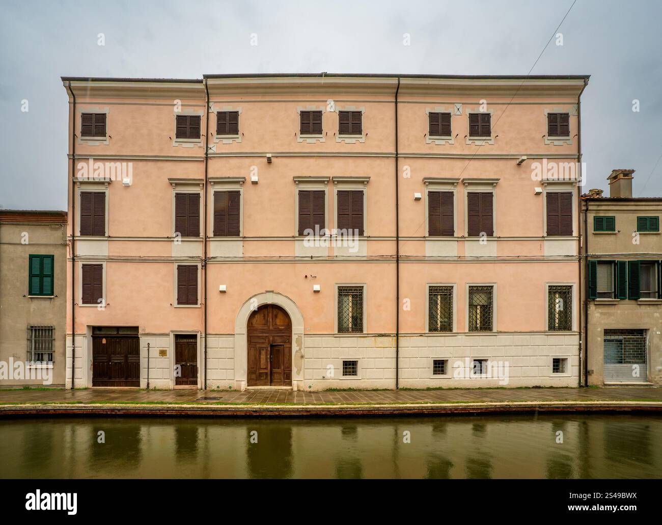 Comacchio, Ferrara – IT – 16. Okt. 2024 Ein ruhiger Kanal in Comacchio, Italien, umgeben von pastellfarbenen Gebäuden und ruhigen Reflexen, die die Stadt einfangen Stockfoto