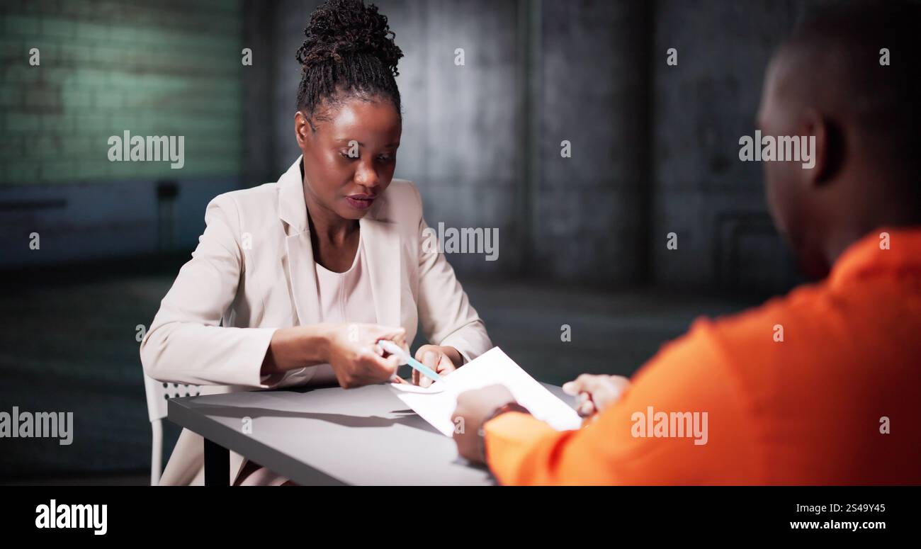Ein Mann Unterschreibt Ein Schuldbekenntnis Im Gefängnis. Polizeiermittler Im Verhörraum Stockfoto