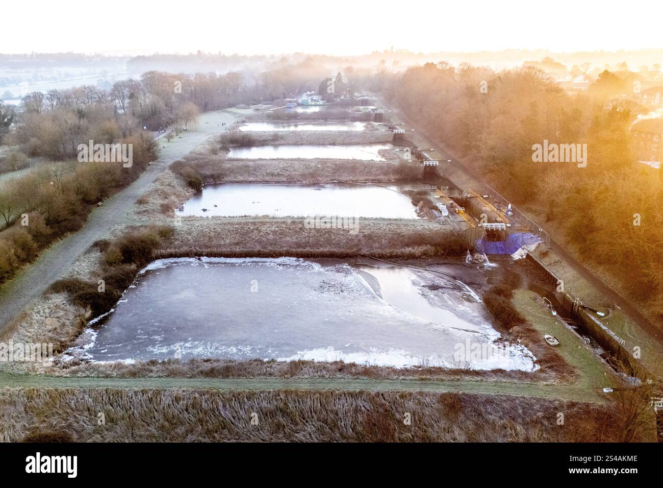 Eis bildet sich auf dem Wasser, wenn die Temperatur während des Sonnenaufgangs -4 °C (minus vier) erreicht, über den 16 Schleusen, die den steilsten Teil des Fluges bei Caen Hill Locks in Devizes, Wilsthire bilden, einer der längsten durchgehenden Schleusen des Landes. Die Caen Hill Schleusen am Kennet und Avon Canal bestehen aus insgesamt 29 Schleusen, die sich über einen Verlauf von 3 Meilen 237 m bei einer Steigung von 1 zu 44 m erheben. Bilddatum: Samstag, 11. Januar 2025. Stockfoto