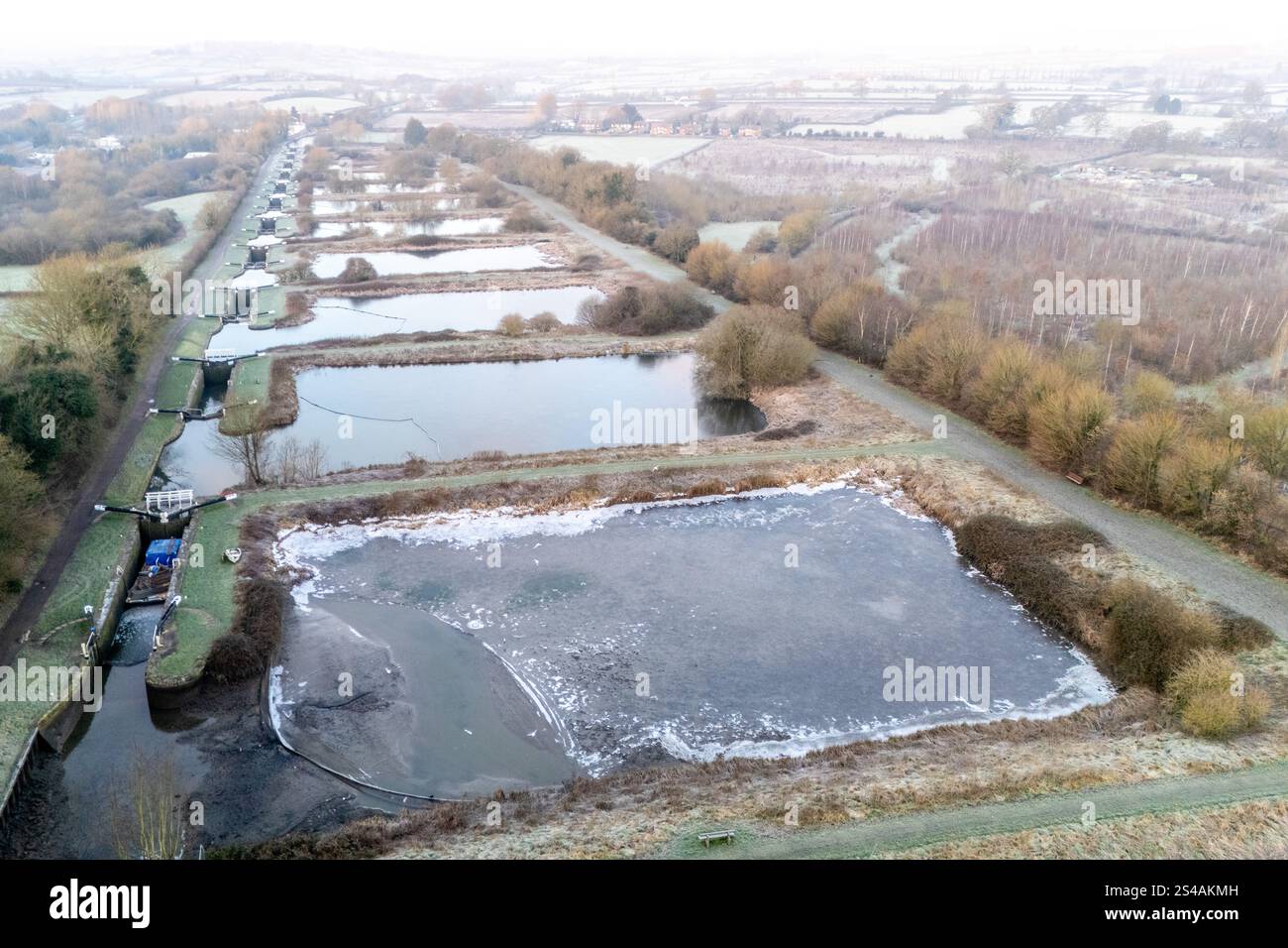 Eis bildet sich auf dem Wasser, wenn die Temperatur während des Sonnenaufgangs -4 °C (minus vier) erreicht, über den 16 Schleusen, die den steilsten Teil des Fluges bei Caen Hill Locks in Devizes, Wilsthire bilden, einer der längsten durchgehenden Schleusen des Landes. Die Caen Hill Schleusen am Kennet und Avon Canal bestehen aus insgesamt 29 Schleusen, die sich über einen Verlauf von 3 Meilen 237 m bei einer Steigung von 1 zu 44 m erheben. Bilddatum: Samstag, 11. Januar 2025. Stockfoto