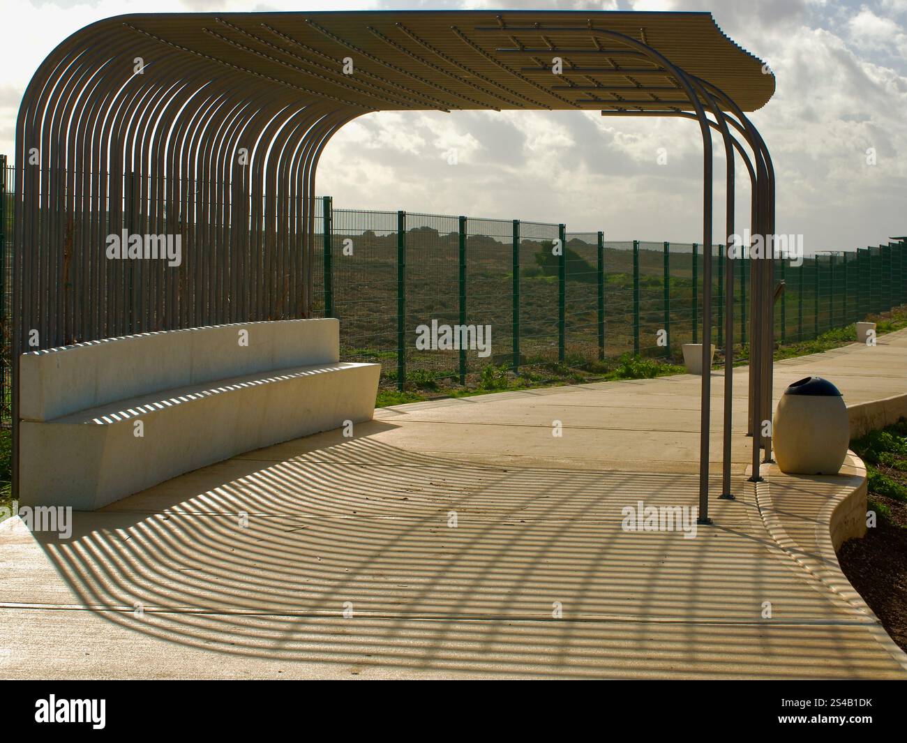 Moderne Sitzbank im Freien mit Metallschirm und einzigartigen Schattenmustern Stockfoto