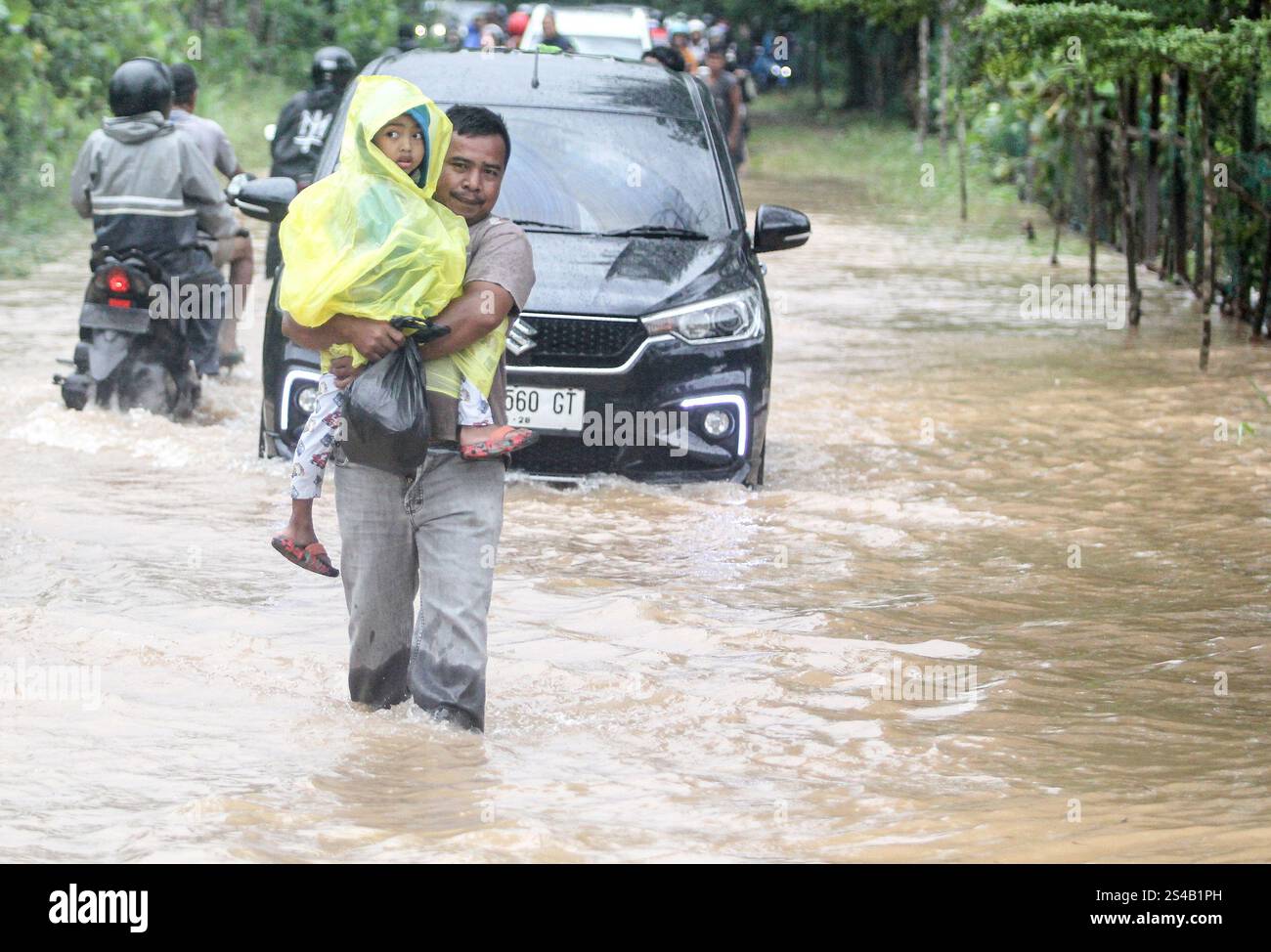 Tanjungpinang, Indonesien. Januar 2025. Ein Vater, der sein Kind hält, geht durch das Hochwasser, nachdem der starke Regen Tanjungpinang, die Hauptstadt der indonesischen Provinz Riau, am 11. Januar 2025 getroffen hat. Quelle: Yuli Seperi/Xinhua/Alamy Live News Stockfoto