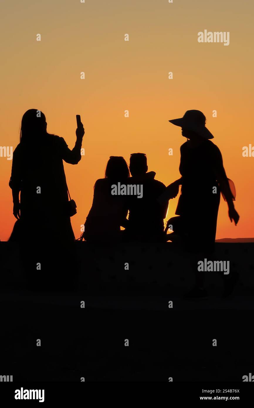 Silhouettenfiguren, abendliche Zuschauer beobachten den Sonnenuntergang in Oia, Santorin, Griechenland – 27. September 2023 Stockfoto