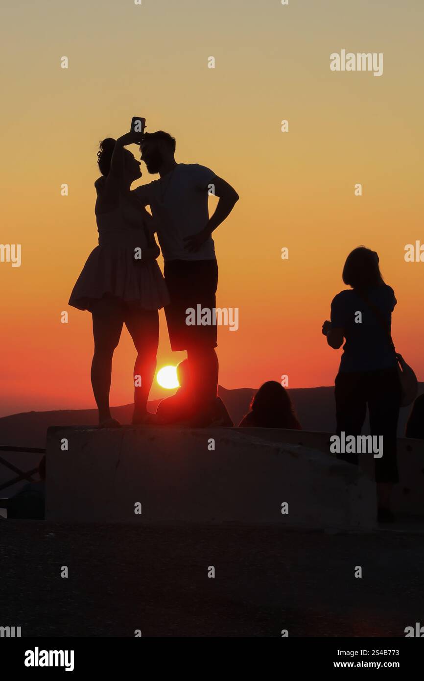 Silhouettenfiguren, abendliche Zuschauer beobachten den Sonnenuntergang in Oia, Santorin, Griechenland – 27. September 2023 Stockfoto