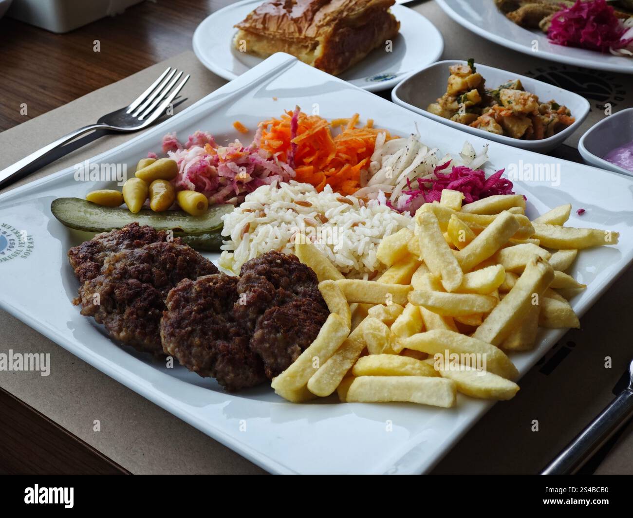 Ein Teller Köfte, ein türkisches Gericht mit gegrillten Lammpatties, serviert mit Gemüsesalat, Reispilav und Pommes frites Stockfoto