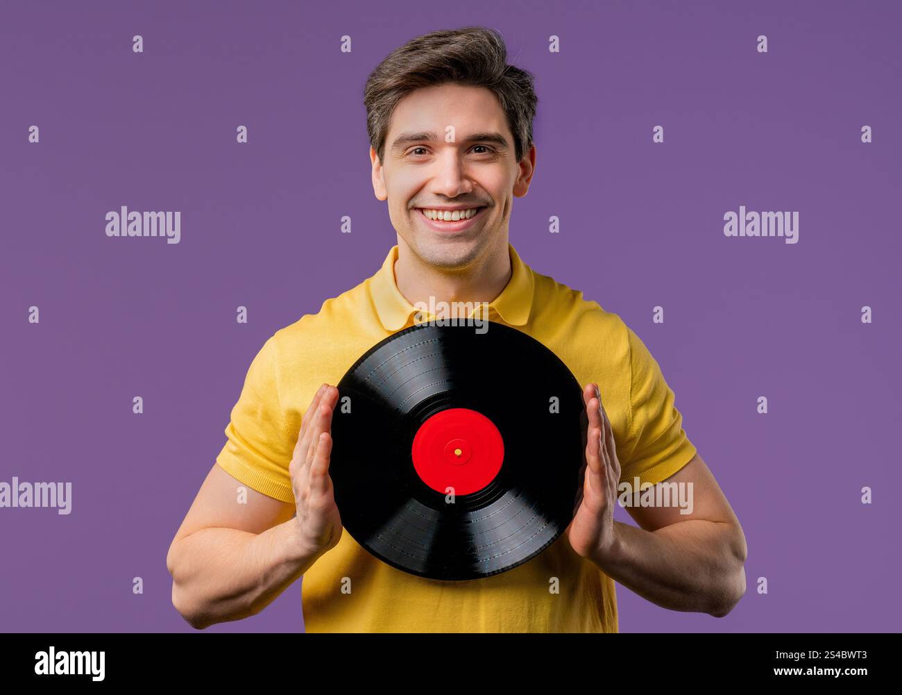 Schöner reifer Mann, der mit Vinyl-Schallplatte auf Violett tanzt. Hobby, Musikliebhaber, Sammlung, Nostalgie Lifestyle. Hochwertige Fotos Stockfoto