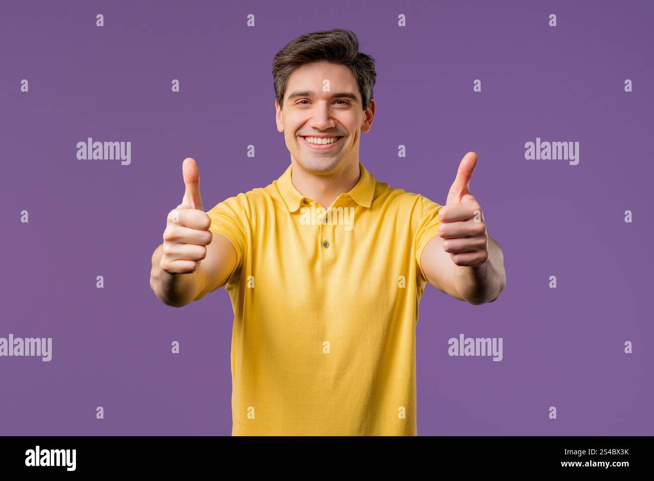 Ein positiver amerikanischer Mann macht Handzeichen wie eine Daumen-hoch-Geste. Glücklicher Studententyp auf Violett, richtige perfekte Wahl, tolles Angebot, Studiohintergrund. Hg Stockfoto