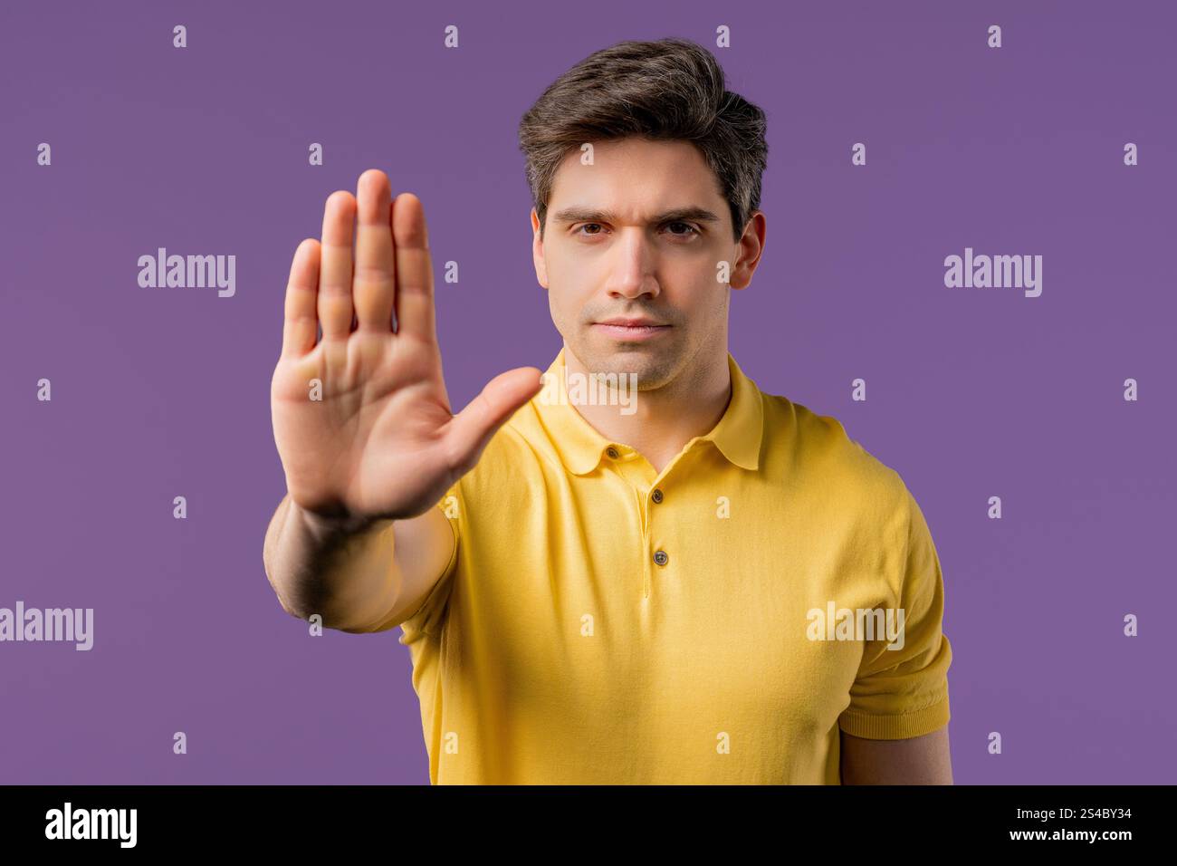 Seriöser europäischer Mann, der eine ablehnende Geste zeigt, mit einem Stoppfinger-Schild. Spiel nicht mit mir. Der Typ ist isoliert auf violettem Hintergrund. Hohe Qualität Stockfoto