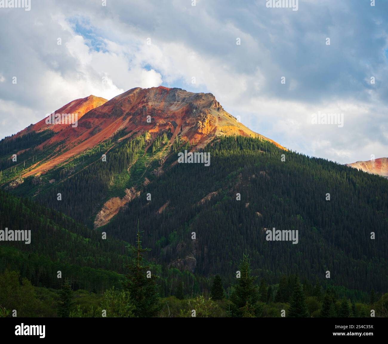 Ein atemberaubender Blick auf den Million Dollar Highway in Colorado mit üppigen Wäldern, zerklüfteten Gipfeln und lebendigen roten Felsformationen. Stockfoto