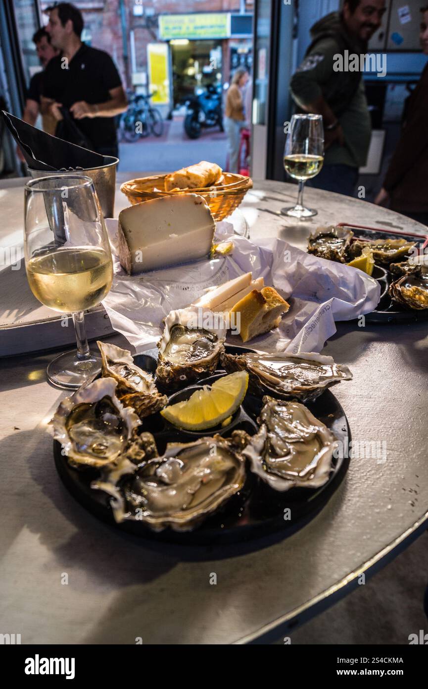 Mittagessen mit Austern, Brot, Käse und Weißwein in der Bar des Vedettes, dem überdachten Markt von Saint-Cyprien, Toulouse, Haute-Garonne, Occitanie, Frankreich Stockfoto