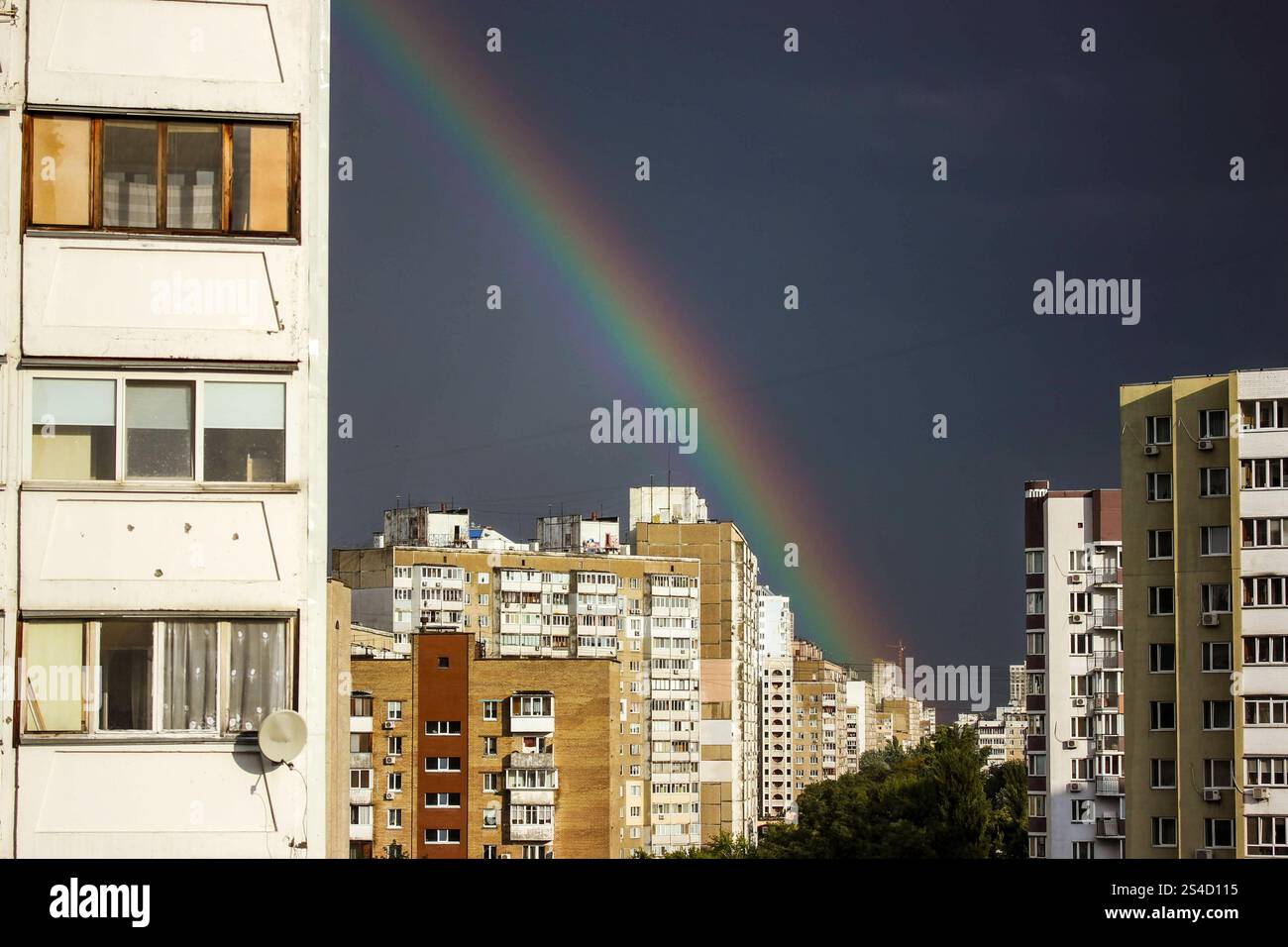Kiew, Ukraine 1. Mai 2024 Blick vom Fenster eines mehrstöckigen Gebäudes auf ein Wohngebiet mit Hochhäusern und einem Regenbogen am blauen Himmel. Stockfoto