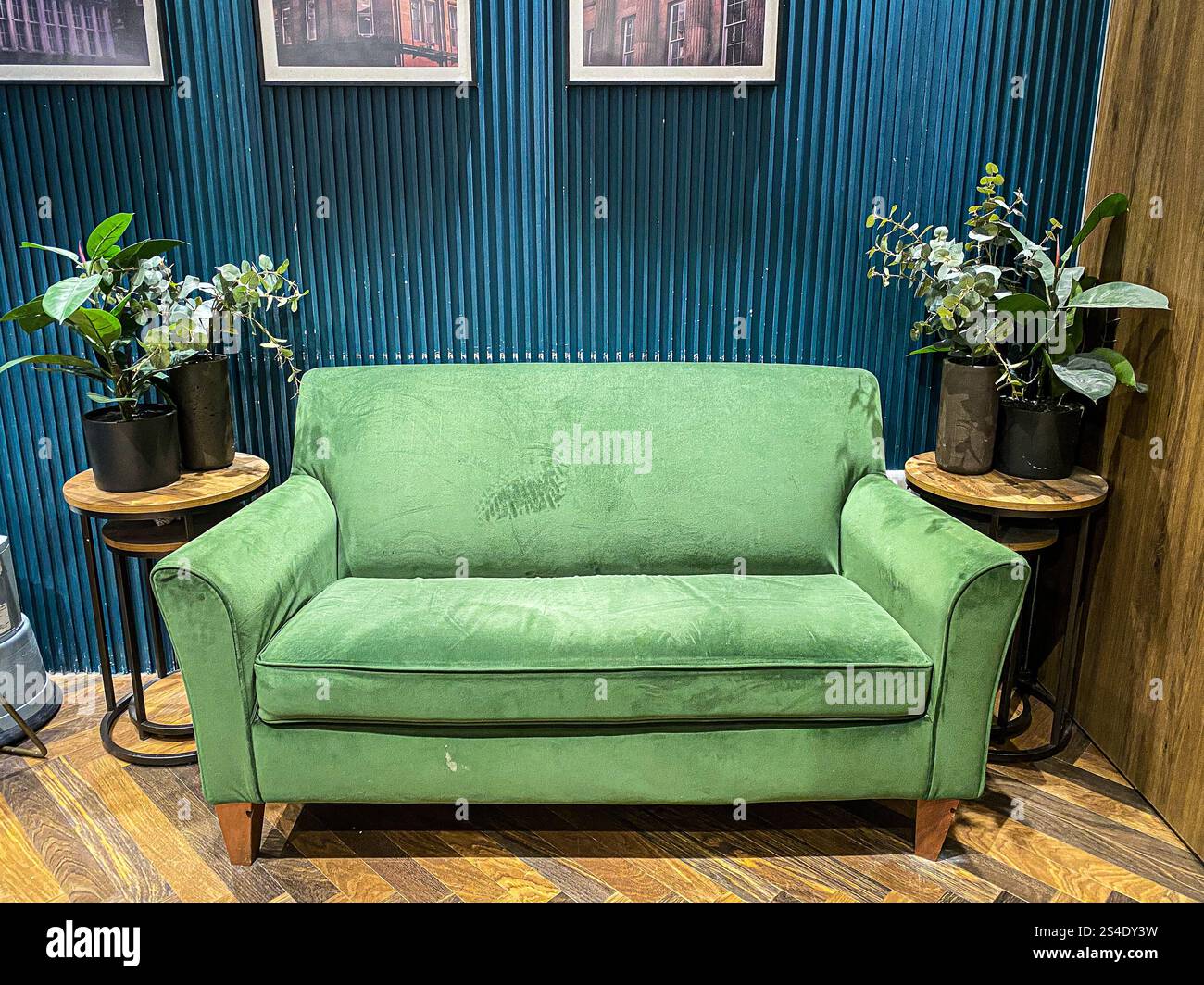 Ein grünes Sofa in einem Wartebereich in einem Umkleideraum in einem Kleiderladen in der Hauptstraße. Stockfoto