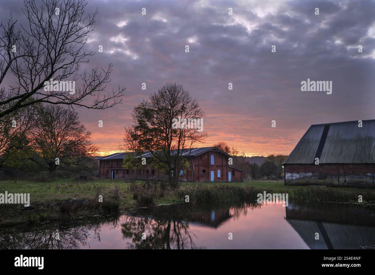 Morgenatmosphäre mit Sonnenaufgang, gut Othenstorf mit Teich und Tierställen, Othenstorf, Mecklenburg-Vorpommern, Deutschland, Europa Stockfoto