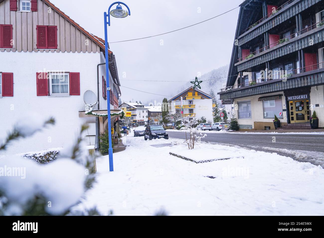 Verschneite Straße mit gemischter Architektur und Dekoration in einer kleinen Stadt, Enzkloesterle, Bezirk Calw, Schwarzwald, Deutschland, Europa Stockfoto