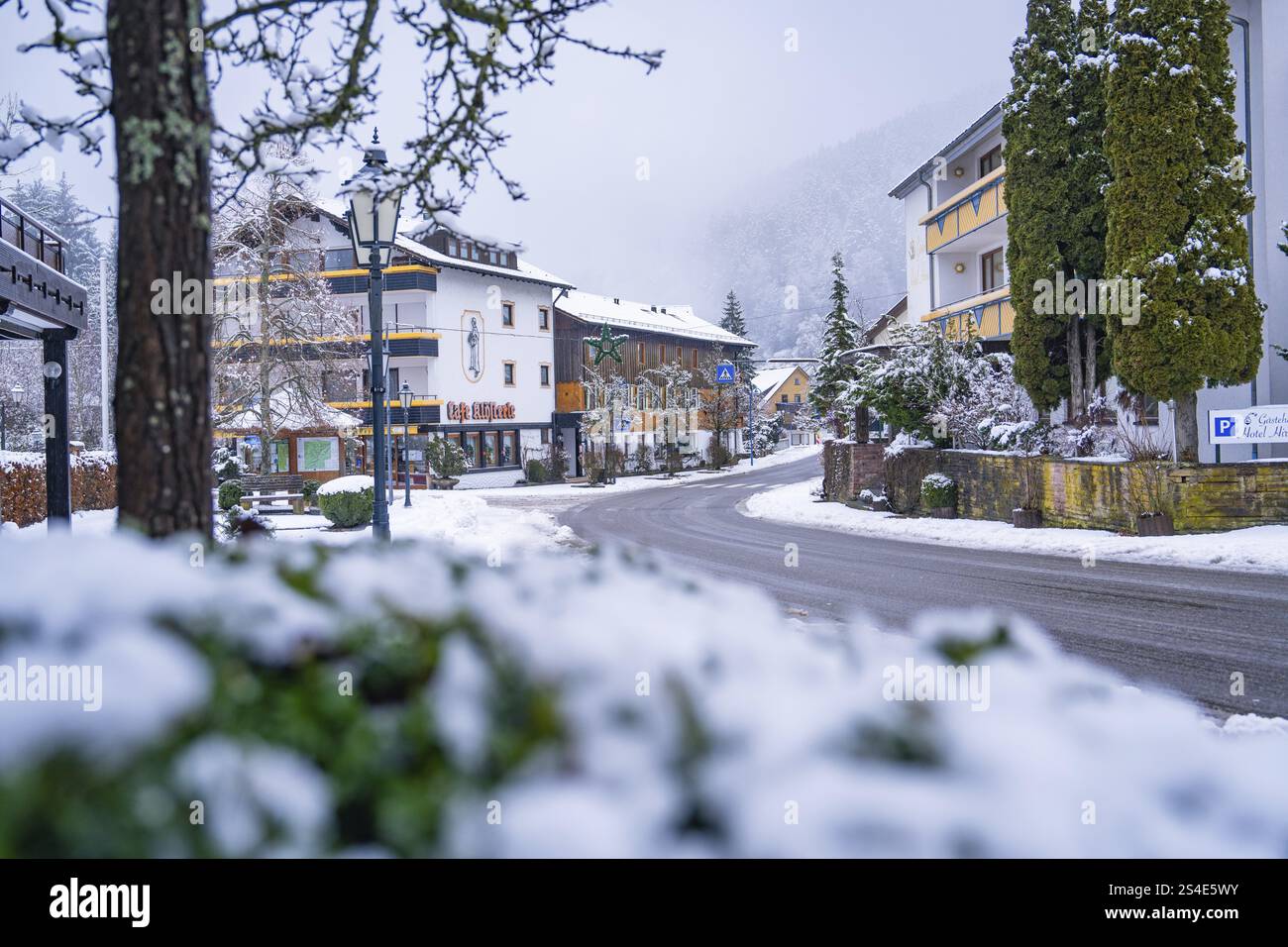 Verschneite Dorfstraße im Winter mit Bäumen und Gebäuden, ruhige Atmosphäre, Enzkloesterle, Bezirk Calw, Schwarzwald, Deutschland, Europa Stockfoto