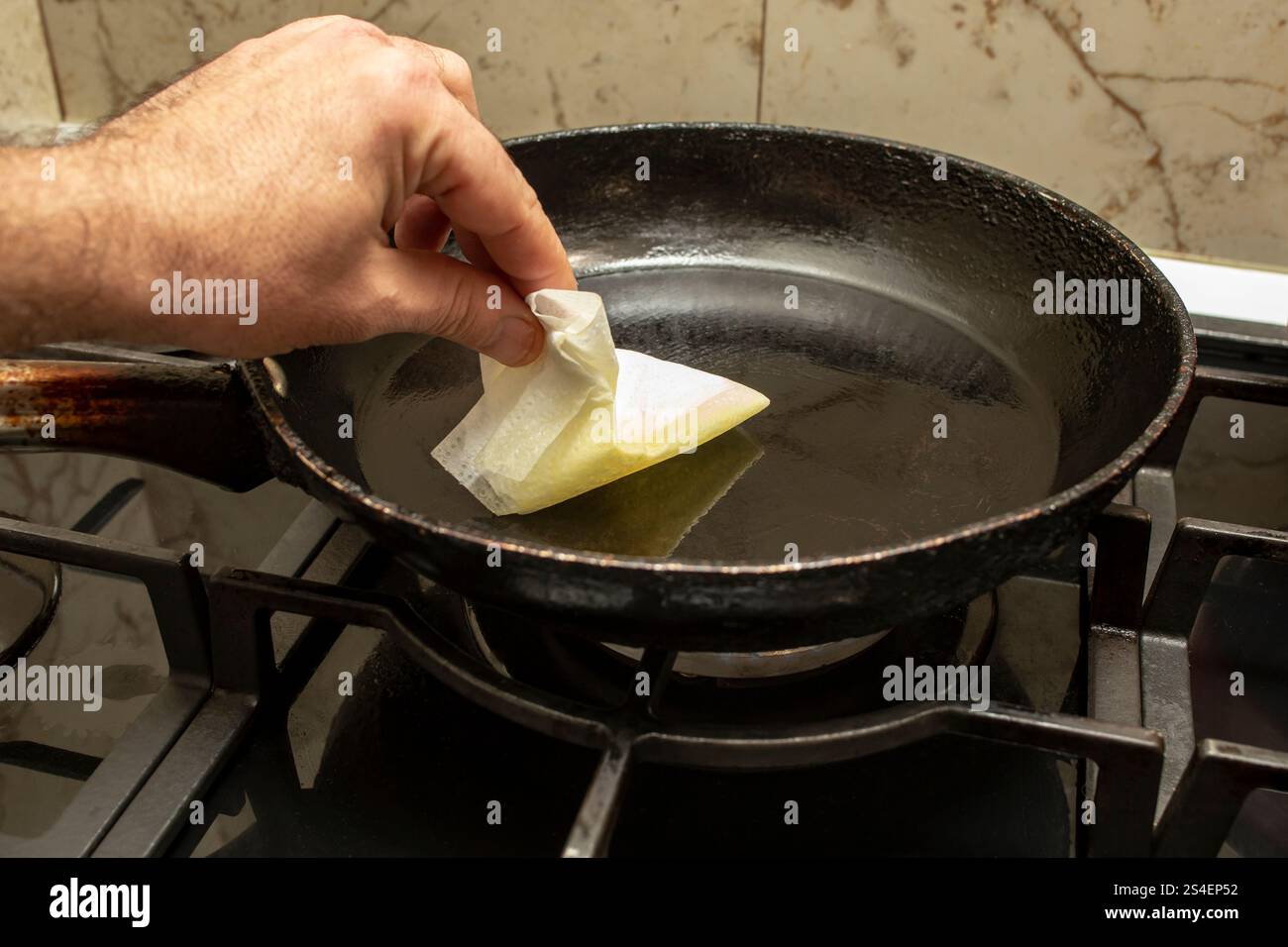 Würzen Sie eine Pfanne mit Pflanzenöl und einem Papiertuch, Antihaftzubereitung Stockfoto