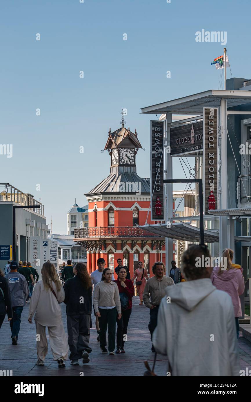 Menschen laufen in der Nähe eines Wahrzeichens der Stadt Clock Tower Waterfront, Historical Monument. Die Abendstraße vor Sonnenuntergang ist voller Touristen. Kapstadt, Sou Stockfoto