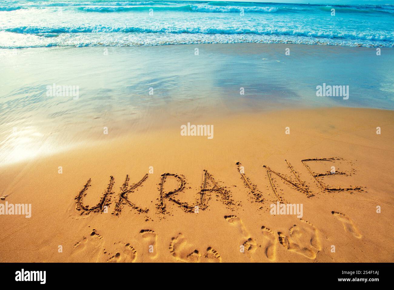 Die Inschrift der Ukraine am Sandstrand. Verlaufsfarbe. Farbe der Flagge der Ukraine Stockfoto