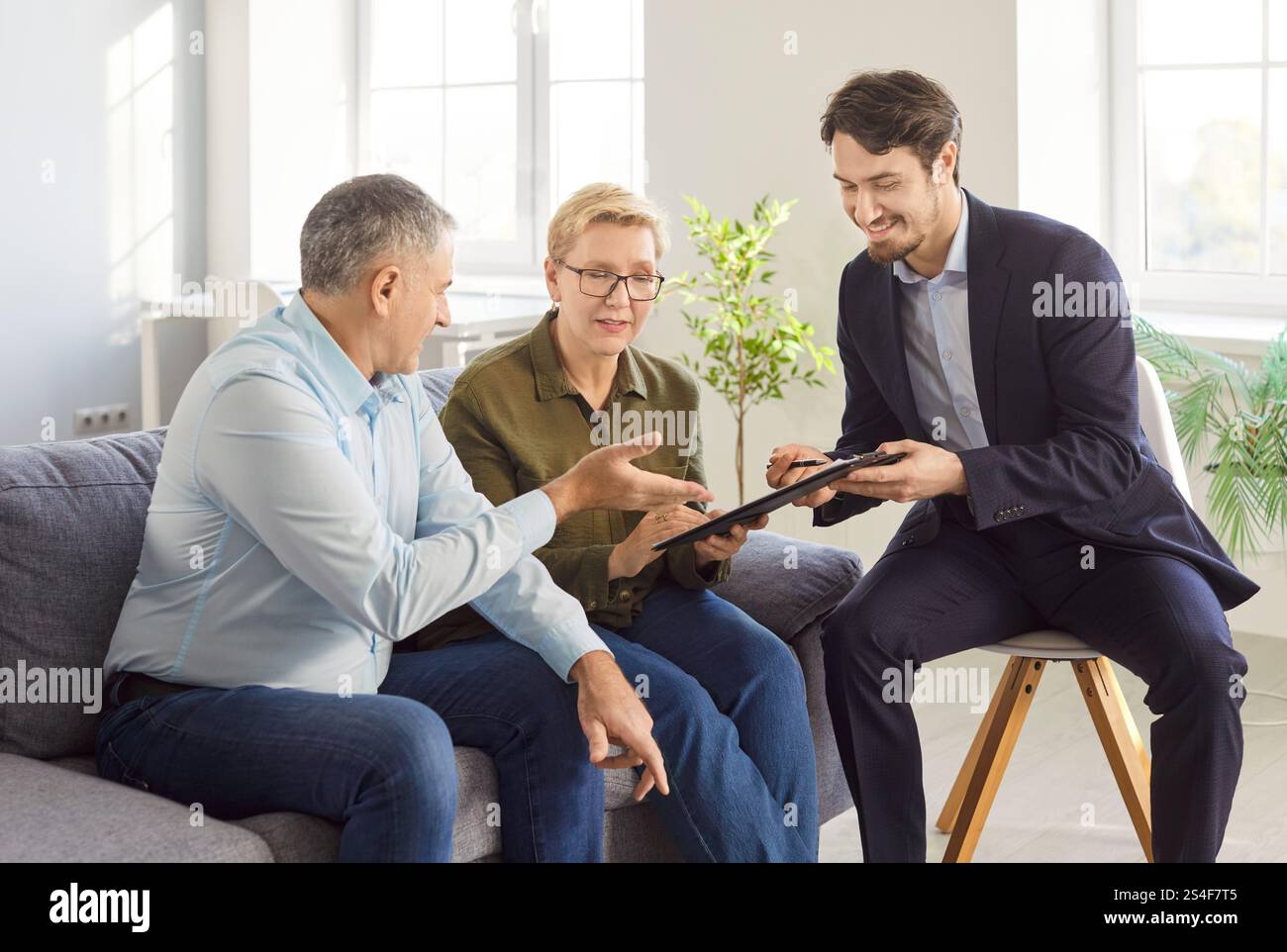 Seniorenpaar im Gespräch mit Finanzagenten über Krankenversicherung im Ruhestand zu Hause. Stockfoto