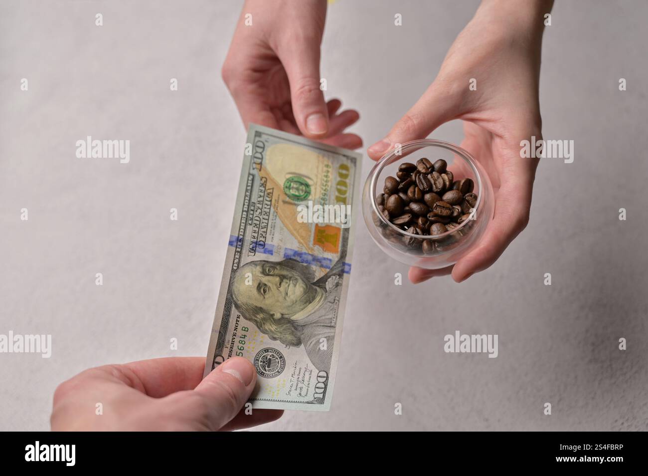 Nahaufnahme ein Mann kauft frische aromatische Kaffeebohnen von einer Frau für 100 US-Dollar Geldscheine, weißer Hintergrund. Steigende Kaffeepreise Stockfoto Nahaufnahme ein Mann kauft frische aromatische Kaffeebohnen von einer Frau für 100 US-Dollar Geldscheine, weißer Hintergrund. Steigende Kaffeepreise Stockfoto