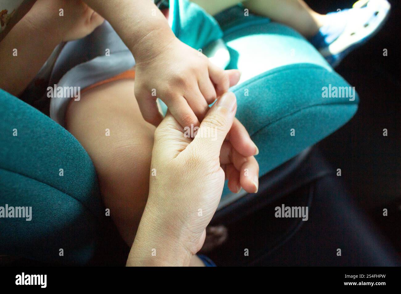 Mutter und Baby sitzen im Auto, Baby Hand in Mutter Hand, Kind sitzt auf einem sicheren Autositz Stockfoto