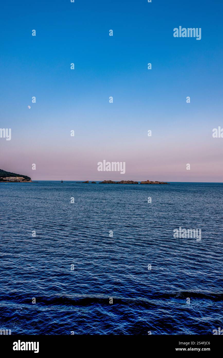 Ein ruhiger Blick auf die Adria am Abend, mit sanften Pastelltönen am Himmel und einem Halbmond, der die ruhige Atmosphäre unterstreicht. Stockfoto