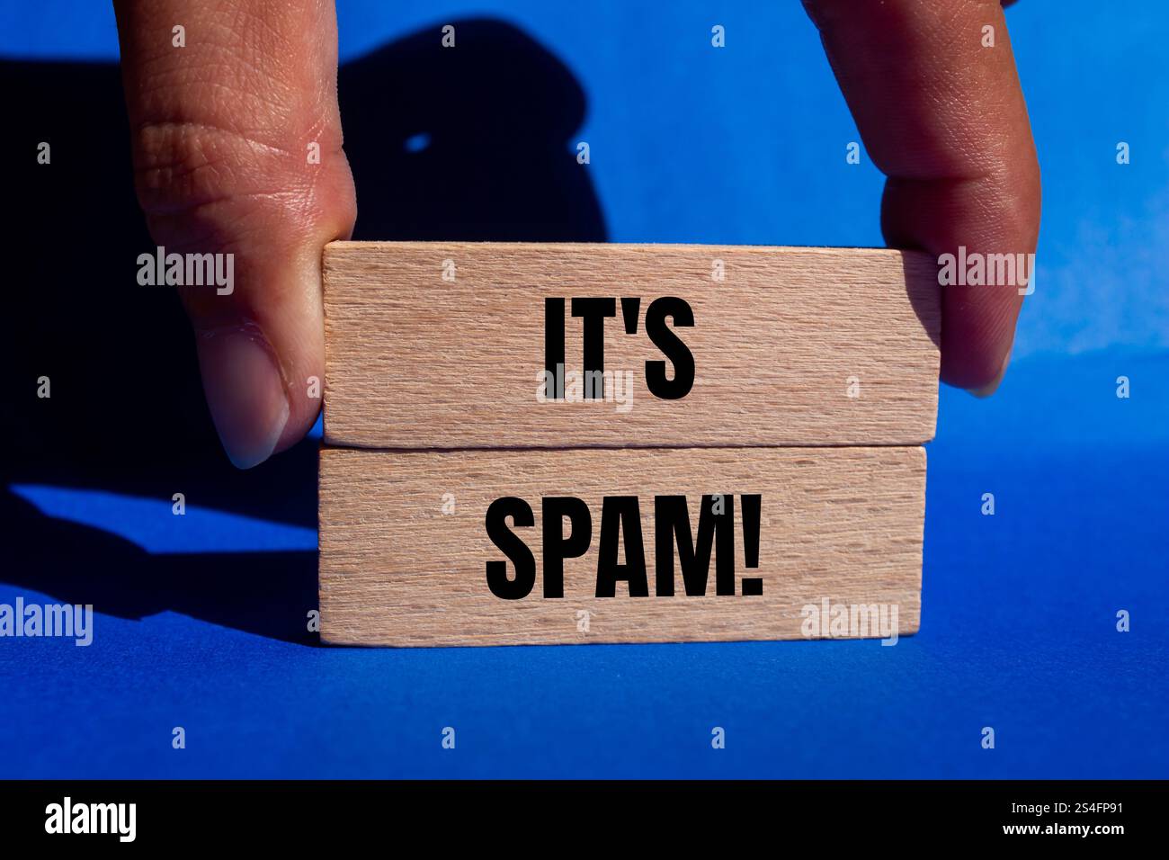 Es ist eine Spam-Nachricht auf Holzblöcken mit blauem Hintergrund. Konzeptionell ist das Spam-Symbol. Kopierbereich. Stockfoto