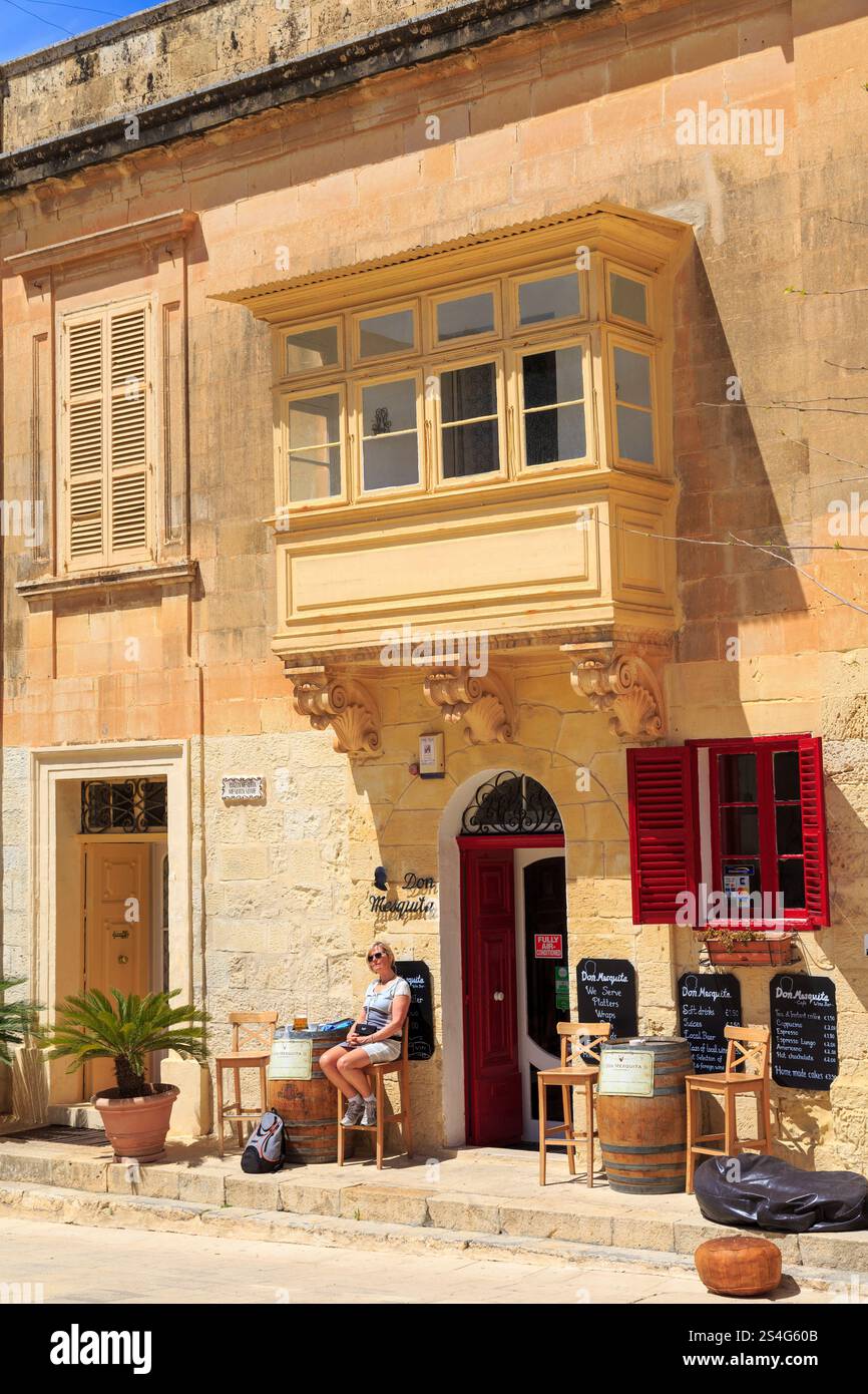 Person, die vor einem Café in der stillen Stadt Mdina, Malta, sitzt Stockfoto