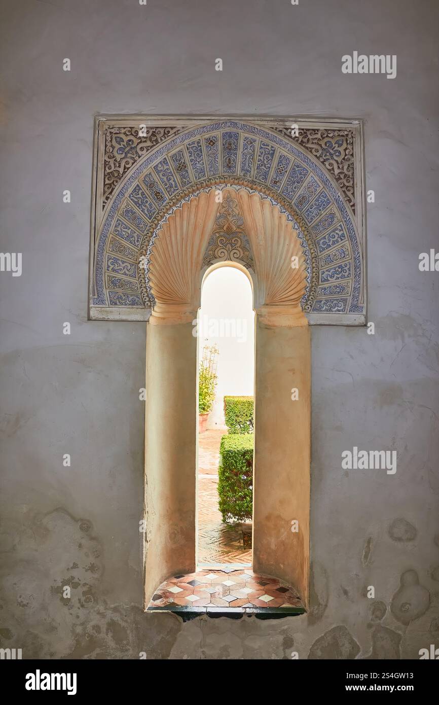 Historisches Bogenfenster mit dekorativem Rahmen mit Blick auf den malerischen Garten auf Gibralfaro Castle, Malaga. Stockfoto