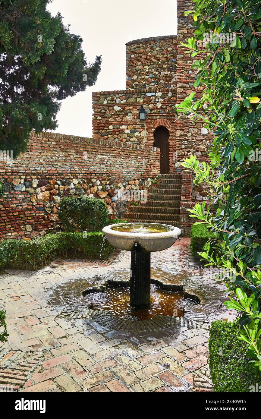 Historischer Steinhof im Schloss Gibralfaro, Malaga mit Brunnen und Grün Stockfoto