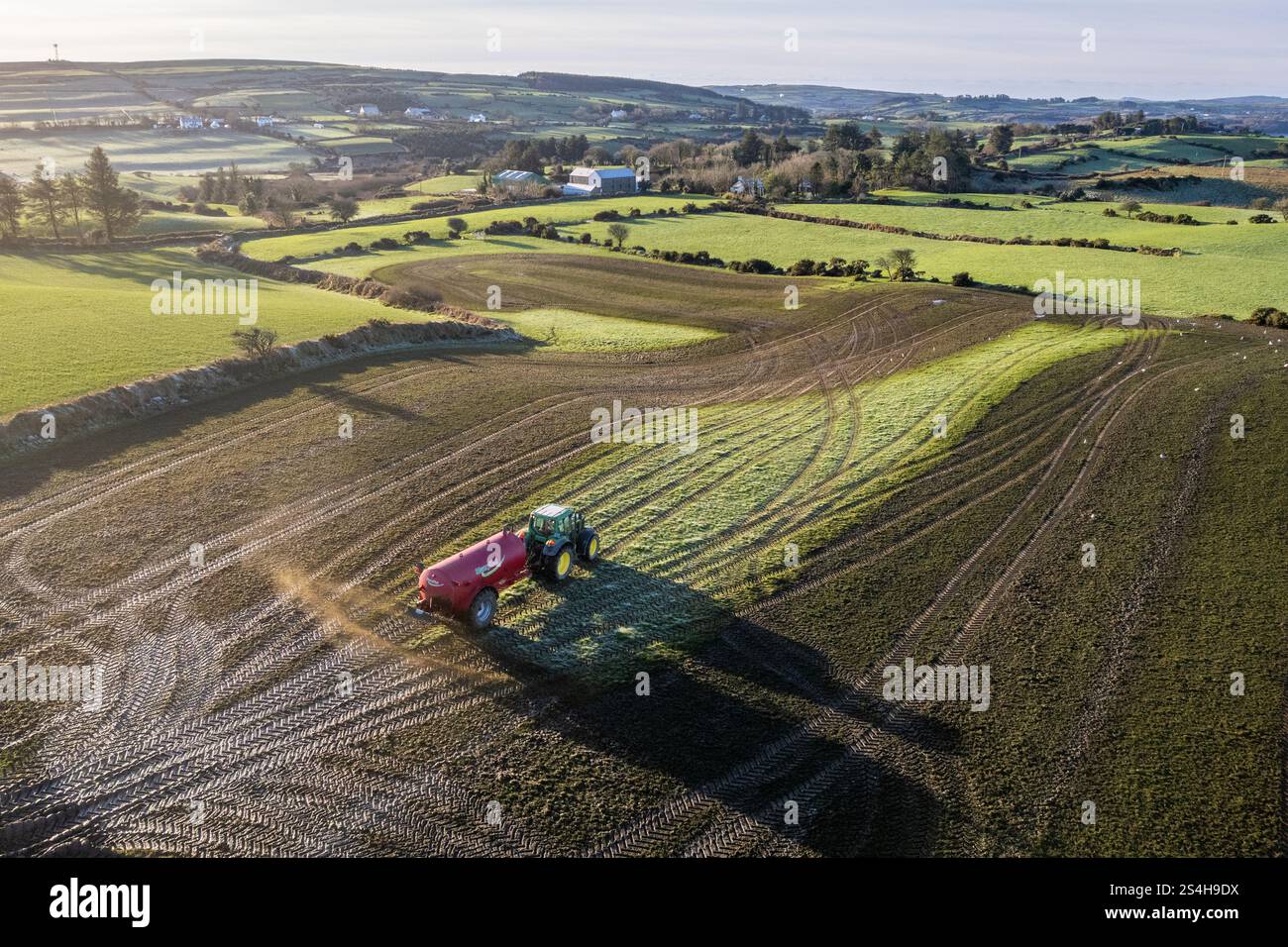 Farmer verteilt Gülle auf einem Feld mit einem Spritzwasserverteiler an einem sonnigen Tag in West Cork, Irland. Stockfoto