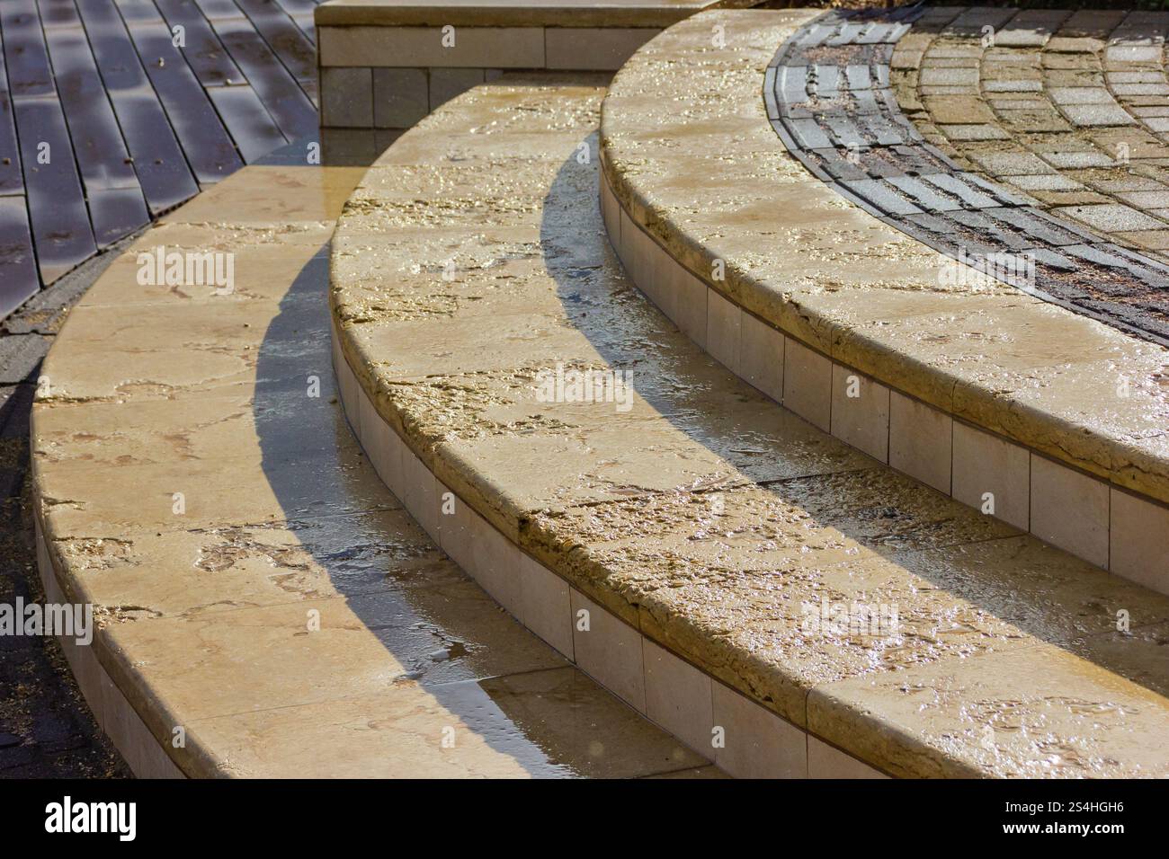 Elegante Steintreppen im Freien mit Sonnenlicht und Details zu nasser Oberfläche Stockfoto