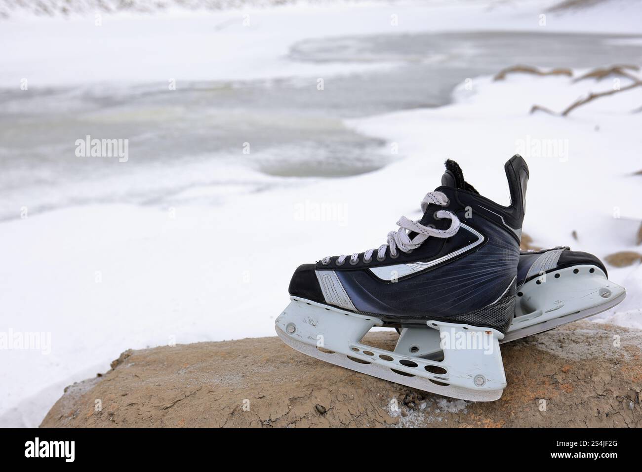 Eishockeyskates bereit für Outdoor-Teichhockey, mit Eis und Schnee im Hintergrund. Stockfoto
