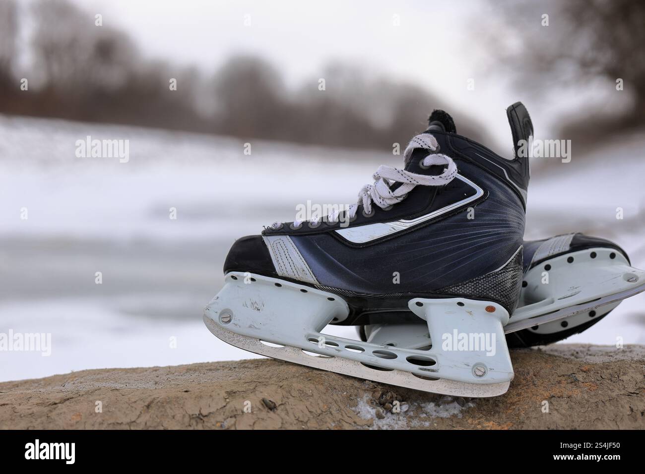 Eishockeyskates bereit für Outdoor-Teichhockey, mit Eis und Schnee im Hintergrund. Stockfoto