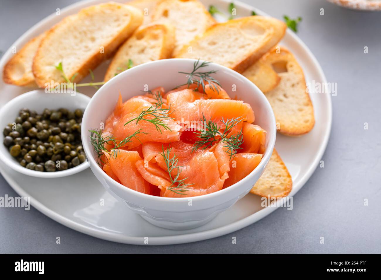 Gourmet-Teller mit geräuchertem Lachs, garniert mit Dill, gepaart mit gerösteten Baguetteschnitten und Kapern Stockfoto