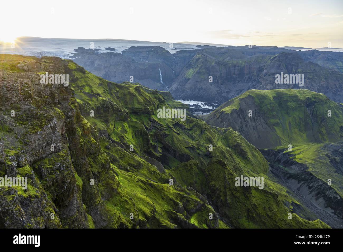 Moosbedeckte Berge bei Sonnenuntergang, Wasserfälle auf einer Klippe am Myrdalsjoekull-Gletscher, Pakgil, Island, Europa Stockfoto