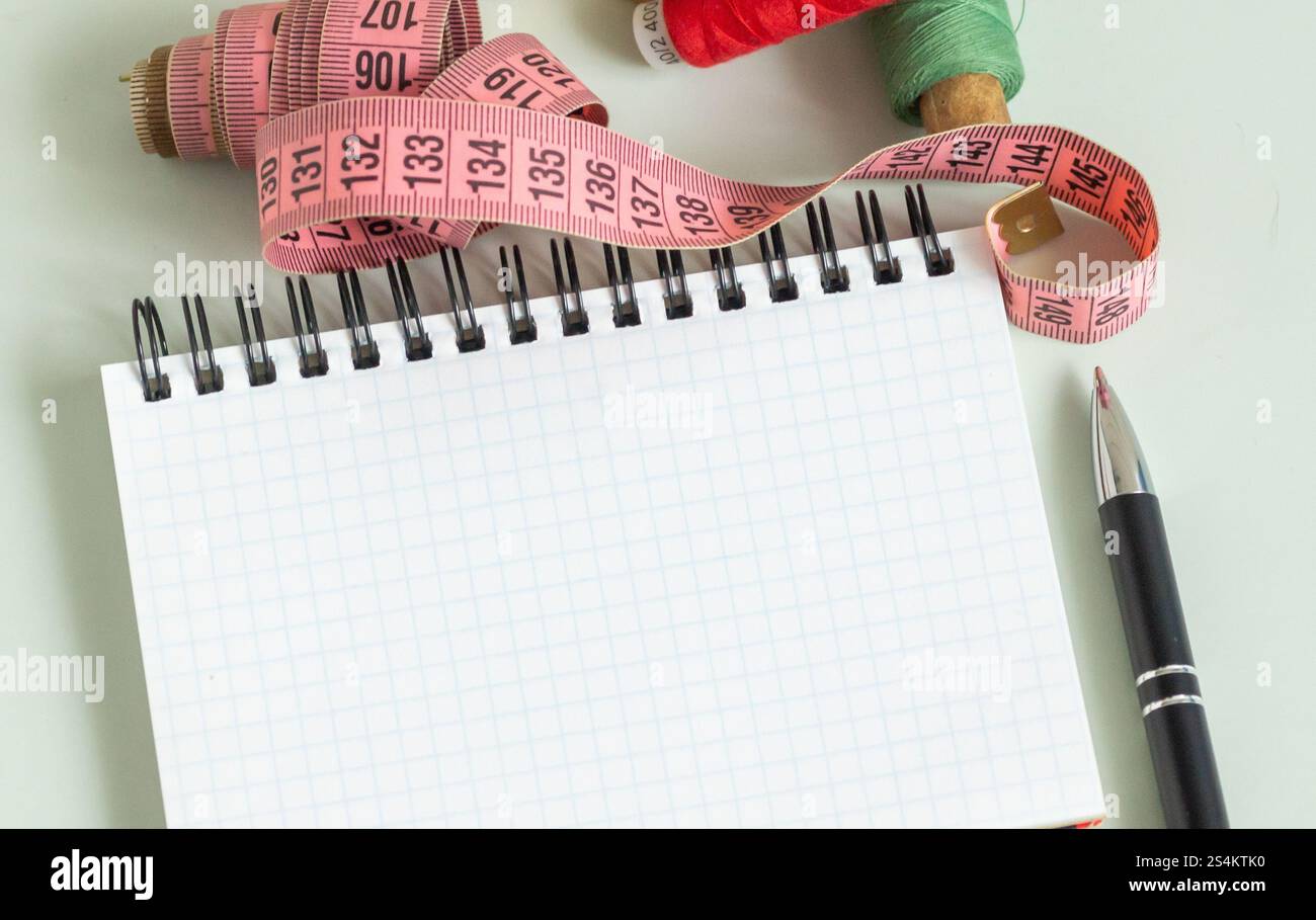 Nähzubehör - Fingerhut, Nadel, Maßband, Spulen aus Fadennotizblock und Stift zum Notizen Stockfoto