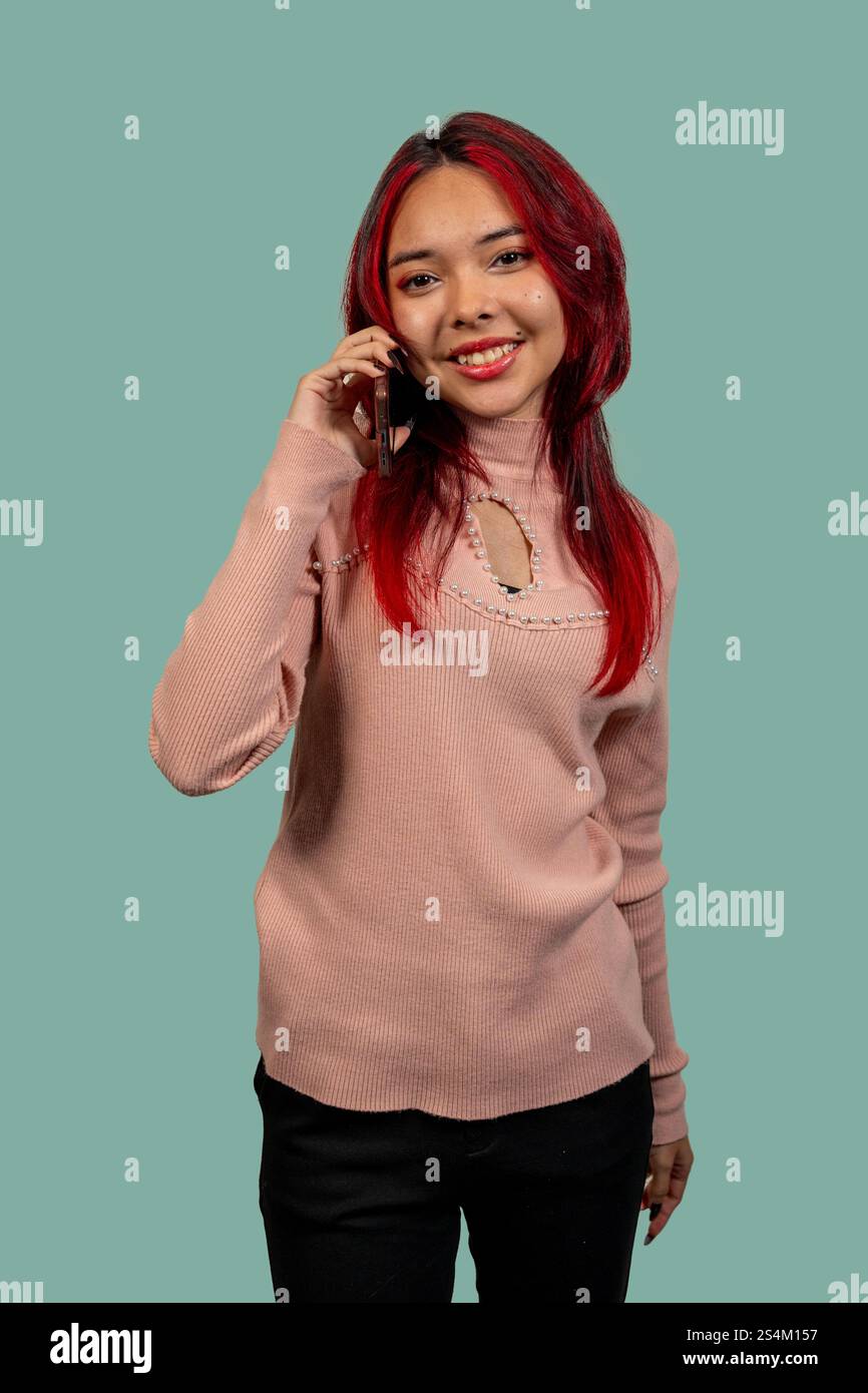 Studio-Aufnahme einer jungen Frau mit rotem Haar mit einem Smartphone, lächelnd und in die Kamera schauend Stockfoto