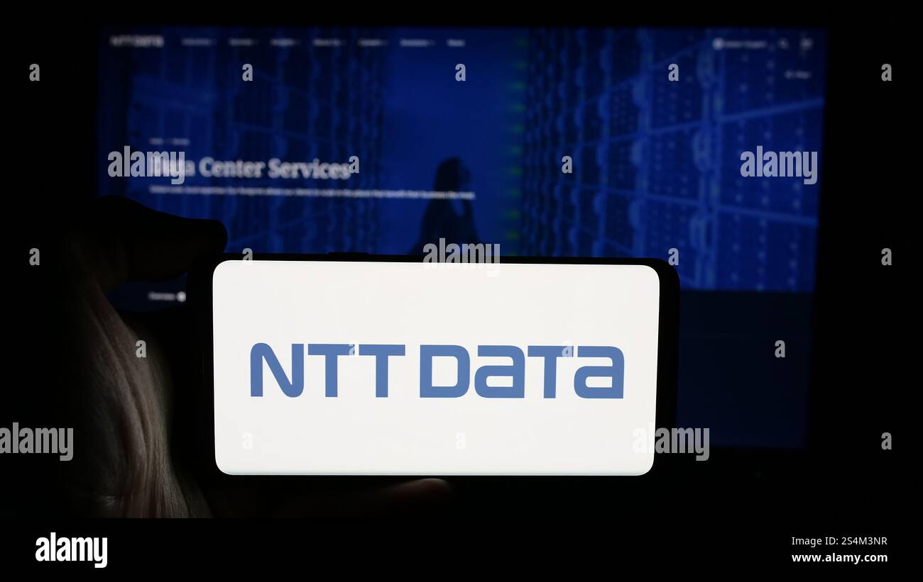 Deutschland. Oktober 2024. In dieser Abbildung hält eine Person ein Mobiltelefon mit dem Logo des japanischen IT-Unternehmens NTT DATA Corporation auf dem Bildschirm vor der Unternehmenswebseite. (Foto von Timon Schneider/SOPA Images/SIPA USA) *** ausschließlich für redaktionelle Nachrichten *** Credit: SIPA USA/Alamy Live News Stockfoto