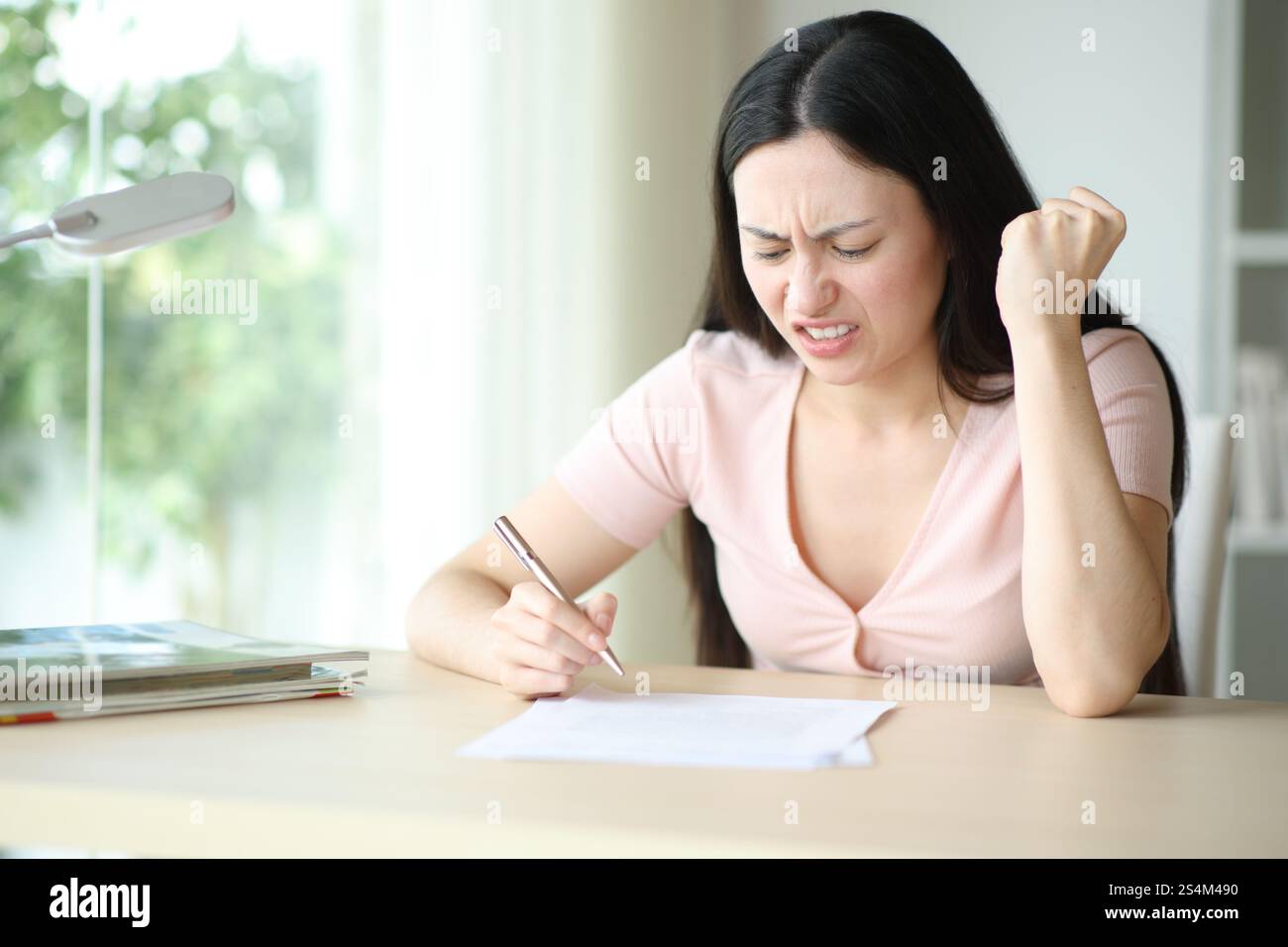 Wütende asiatische Frau liest den Vertrag, bevor sie ihn zu Hause unterschreibt Stockfoto