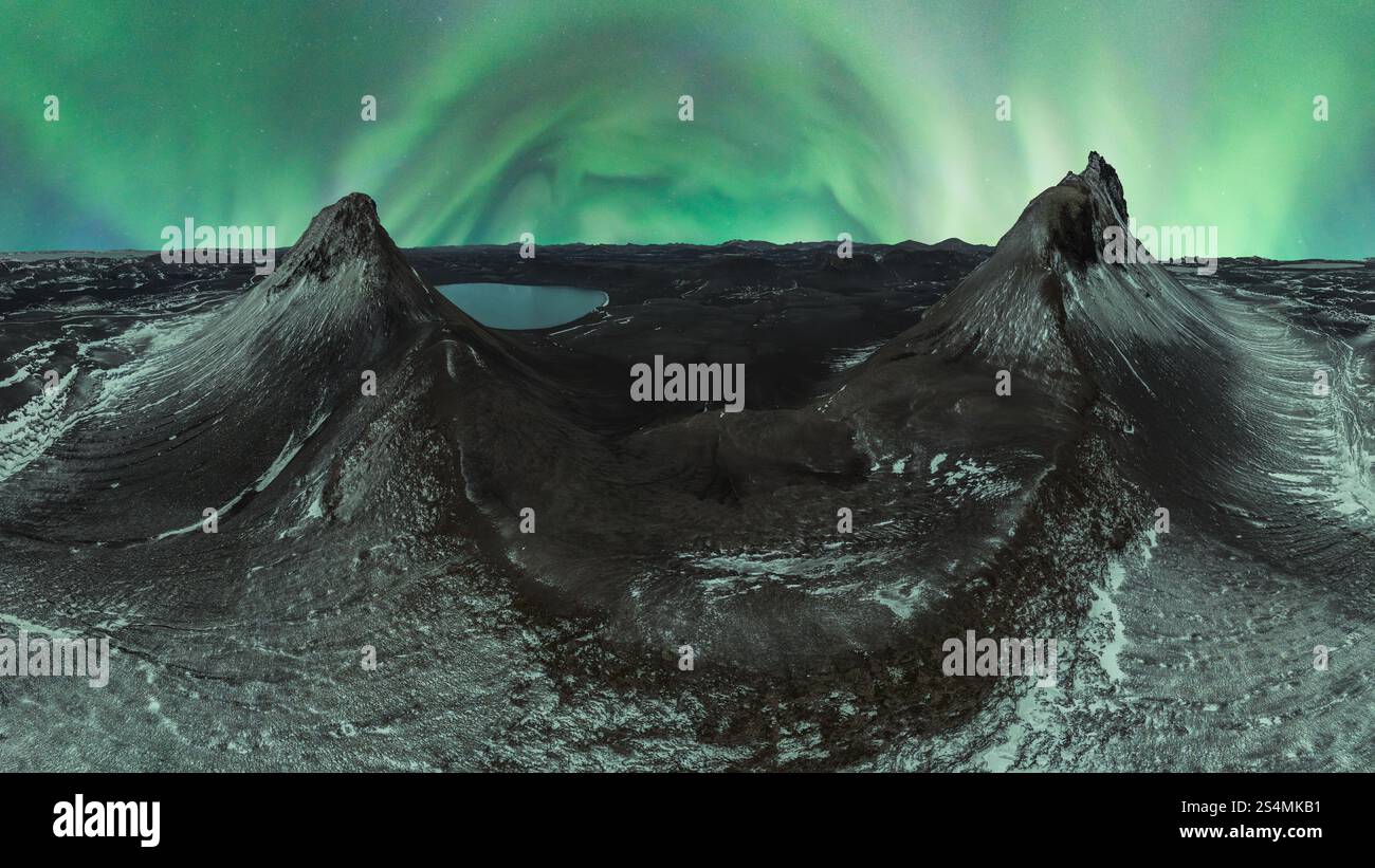 Ein atemberaubendes Panorama der Nordlichter, die über zwei schneebedeckten Gipfeln in der isländischen Wildnis unter einem Sternenhimmel tanzen. Stockfoto