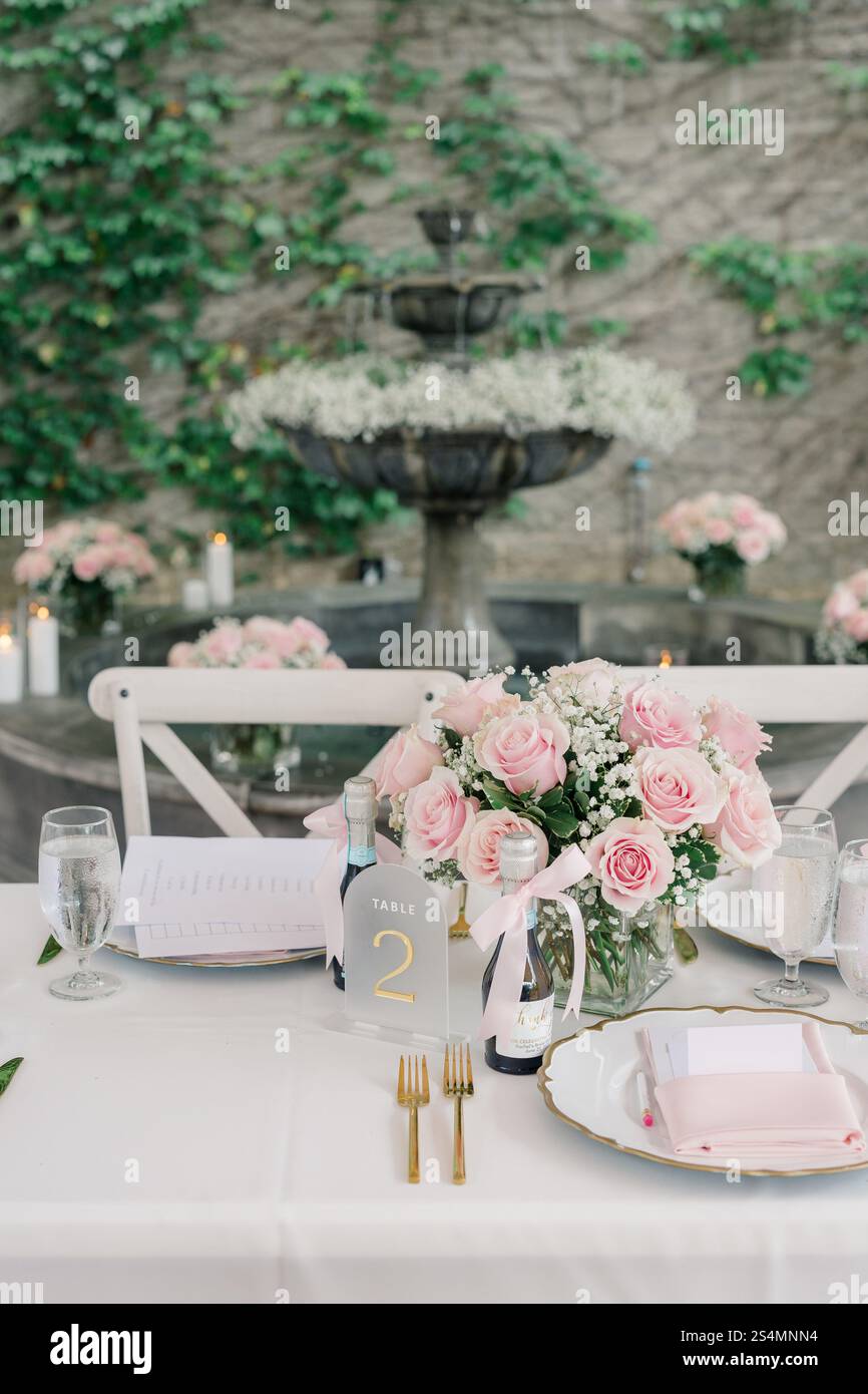 Eleganter Tisch mit rosafarbenen Rosen, goldenen Details und einem Brunnen. Stockfoto